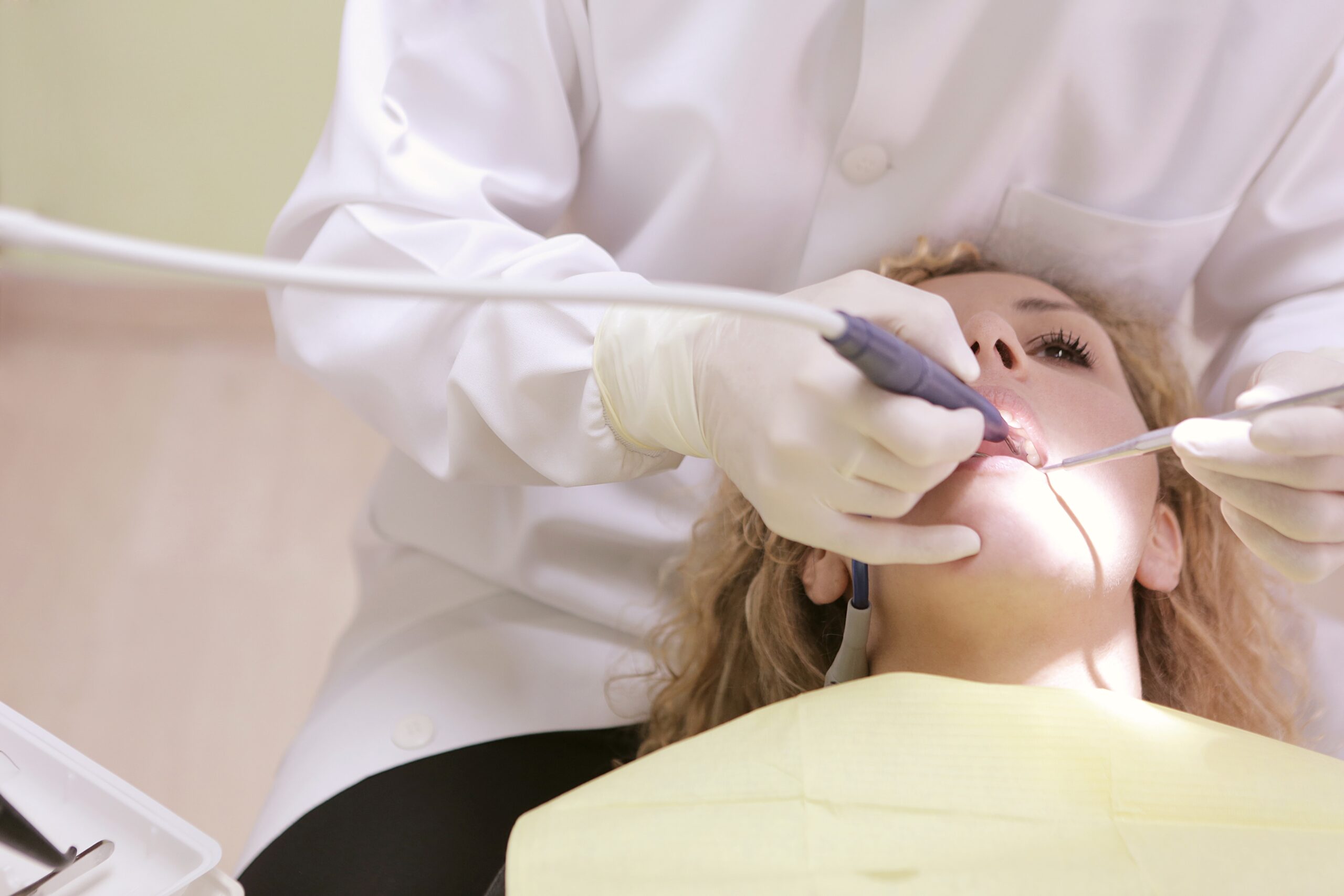 dental hygienist is cleaning girl's teeth