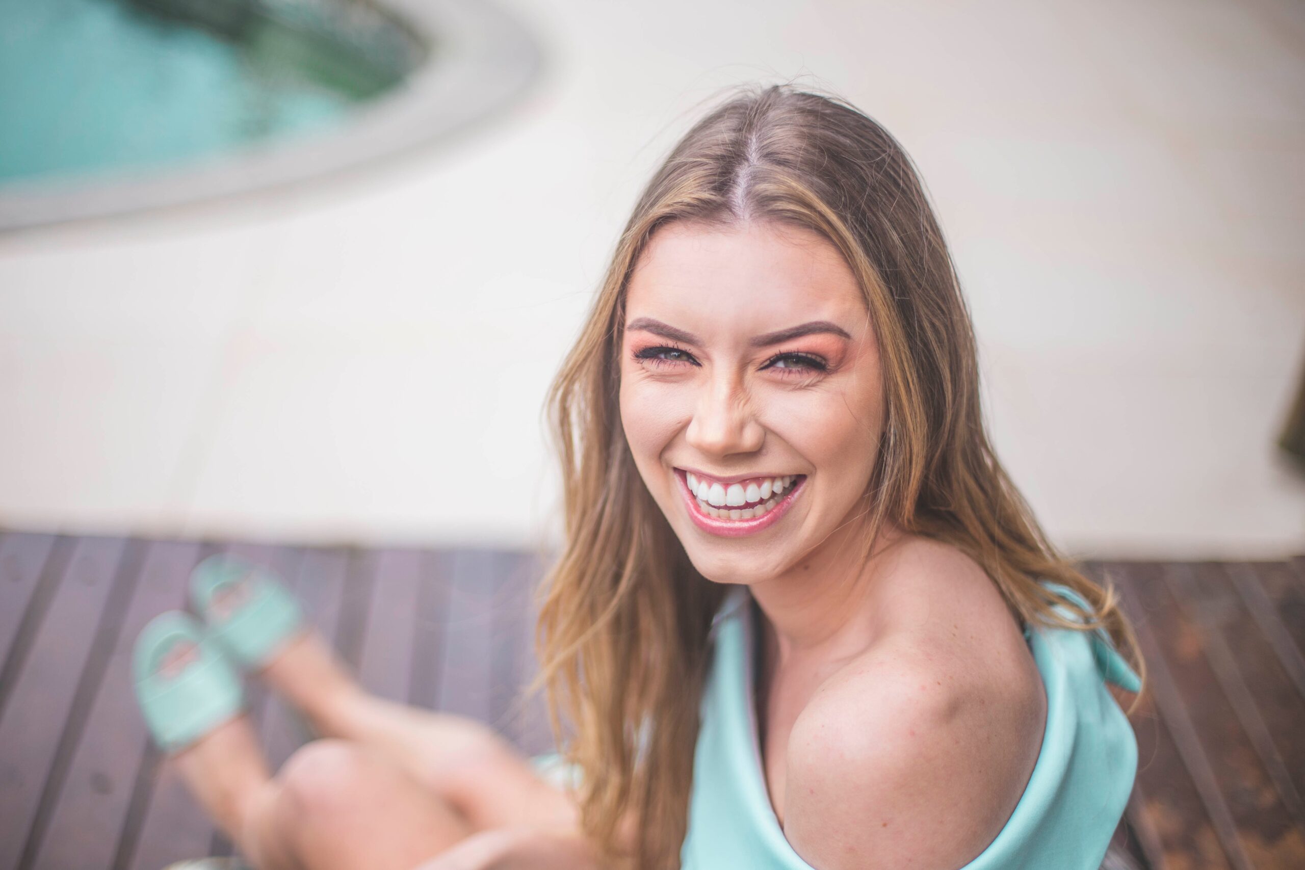 A girl seating, smiling showing her beautiful teeth.